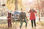 Boys and girl throwing autumn leaves overhead in woods