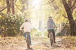 Mother and daughter bike riding on path in woods