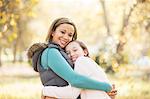 Portrait of smiling mother and daughter hugging outdoors
