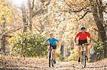 Father and son mountain biking on path in woods