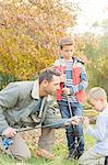 Father teaching sons to prepare fishing rods