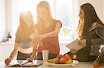 Teenage girls taking selfie with camera phone in kitchen