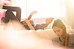 Teenage girls hanging out playing guitar in sunny bedroom