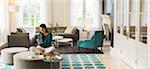 Woman texting on cell phone on ottoman in living room