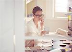 Interior designer examining fabric swatches and talking on cell phone in office