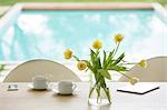 Yellow tulip bouquet and coffee cups on poolside table