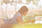 Woman laying using digital tablet on sunny patio