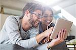 Smiling couple with headphones using digital tablet