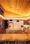 Illuminated slanted wood ceiling over luxury kitchen and dining table