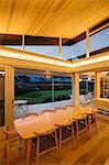 Illuminated slanted wood ceiling over long dining table