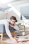 Man with headphones reading newspaper and drinking coffee in living room