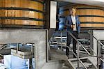 Portrait confident vintner with red wine on platform in winery cellar
