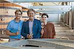 Portrait smiling vintners with white wine in winery cellar