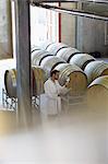 Vintner in lab coat examining white wine in winery cellar