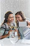 Women with white wine taking selfie with camera phone in restaurant