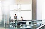 Businesswoman presenting to coworkers in sunny conference room