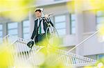 Businessman in suit carrying bicycle in city