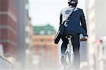 Businessman in suit and helmet riding bicycle in city