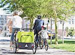 Families riding bicycles in sunny urban park