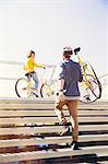 Man in helmet carrying bicycle up urban stairs