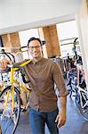Portrait smiling man with eyeglasses carrying bicycle in bicycle shop