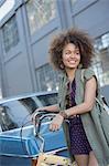 Smiling young woman with afro holding bicycle on urban street