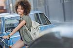 Portrait smiling woman with afro on bicycle in urban street