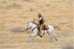 Blurred motion of cowboy on horse galloping in wilderness, Rocky Mountains, Wyoming, USA