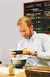 Caucasian man with beard taking pictures of ramen bowl