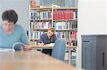 Female students reading textbooks at library desks