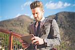 Young man on footbridge reading digital tablet, Rovato, Brescia, Italy