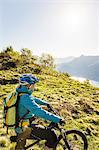 Young woman on mountain bike, looking at view, Lake Como, Italy