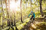 Young woman riding mountain bike through woods, Lake Como, Italy