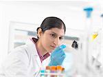 Young woman scientist viewing blood slide during clinical testing of medical samples in a laboratory