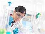 Young woman scientist  pipetting sample into vial in a laboratory used for chemical and DNA testing