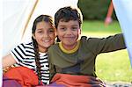 Girl and brother wrapped in blanket in homemade tent