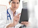 Female doctor using digital tablet touchscreen for medical records