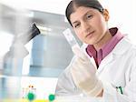 Female scientist in lab testing blood sample using microscope