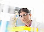 Female scientist holding up and examining chemical sample in lab