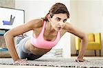 Young woman exercising on living room floor in front of computer screen
