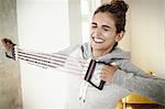 Young woman straining to exercise with chest expander in living room