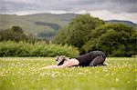 Mature woman practicing yoga childs position in field