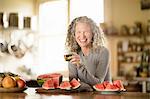 Portrait of mature woman eating watermelon in kitchen