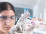 Female scientist testing medical drug ampule in laboratory