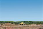 Digger burying waste on landfill site