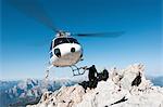 Helicopter dropping BASE jumpers on mountain, Dolomites, Italy