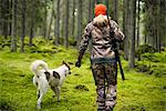 Woman with hunting dog in forest