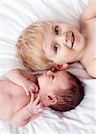 Boy with newborn baby on bed