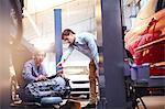 Mechanics discussing engine part in auto repair shop