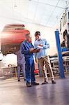 Mechanic with clipboard talking to customer in auto repair shop